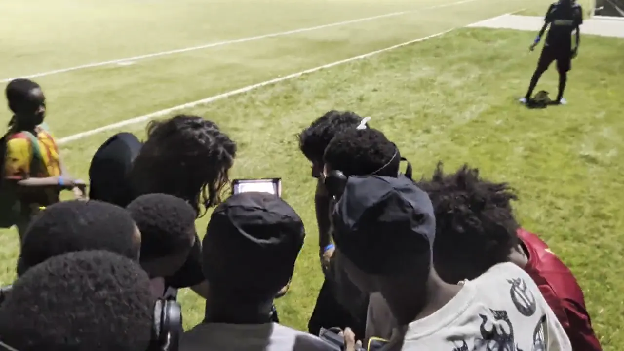 Umoja players gathered pitchside, 2026